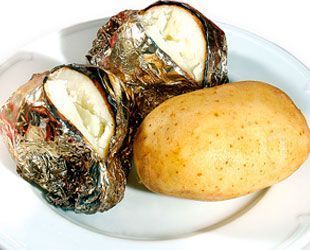 Papas al horno, dos envueltas en papel de aluminio y una simple, en un plato blanco.