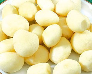 Patatas peladas, de color amarillo claro, recién preparadas y apiladas en una toma de primer plano.