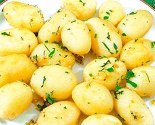 Papas baby doradas asadas y condimentadas con hierbas en un plato blanco.