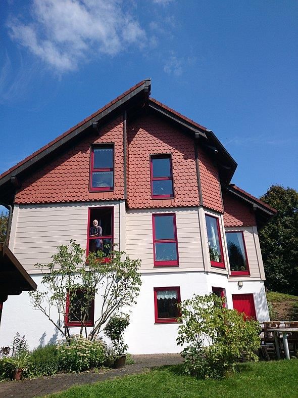 Ein großes Haus mit roten Fenstern und einem blauen Himmel im Hintergrund