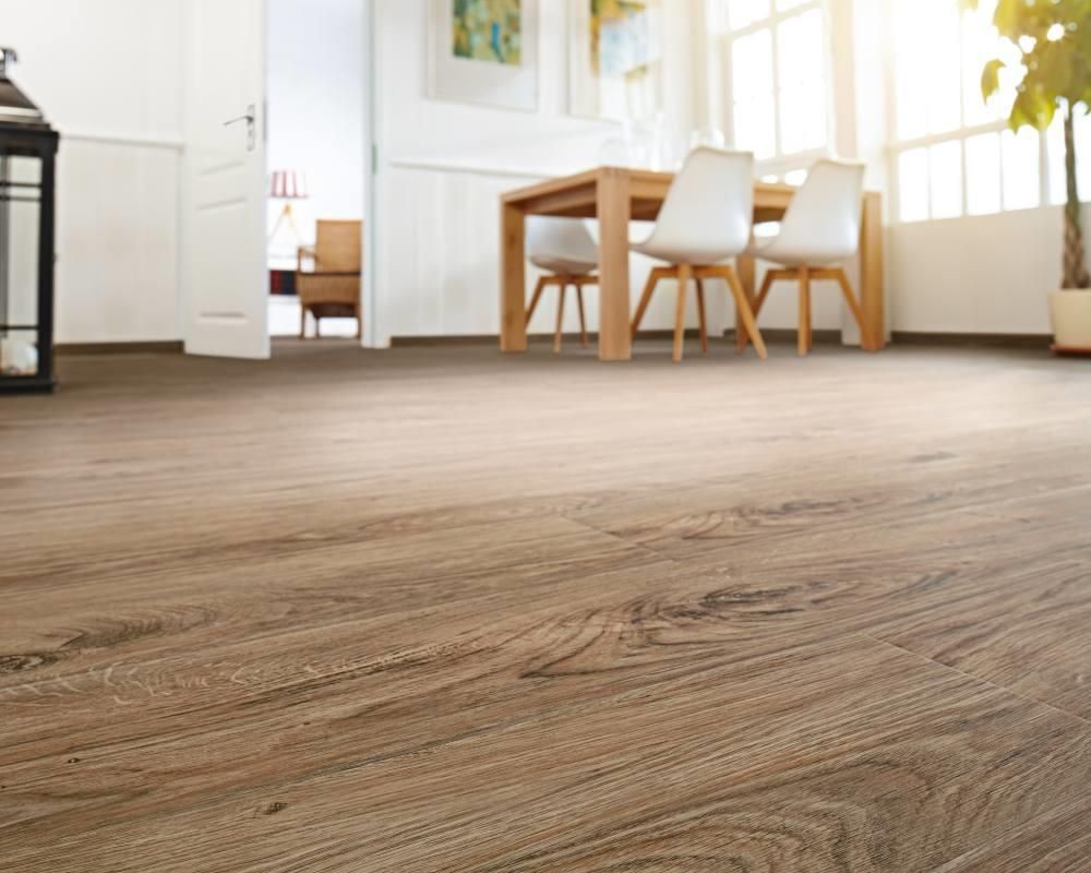 Ein Wohnzimmer mit Holzboden und einem Tisch und Stühlen