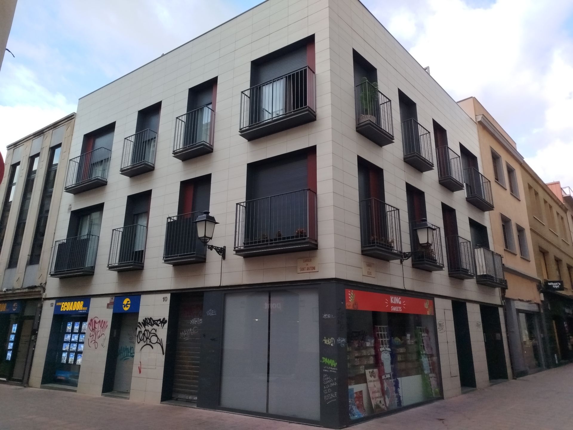 Edificio con balcones y locales cerrados en esquina, se ven un Lidl y una tienda de conveniencia.