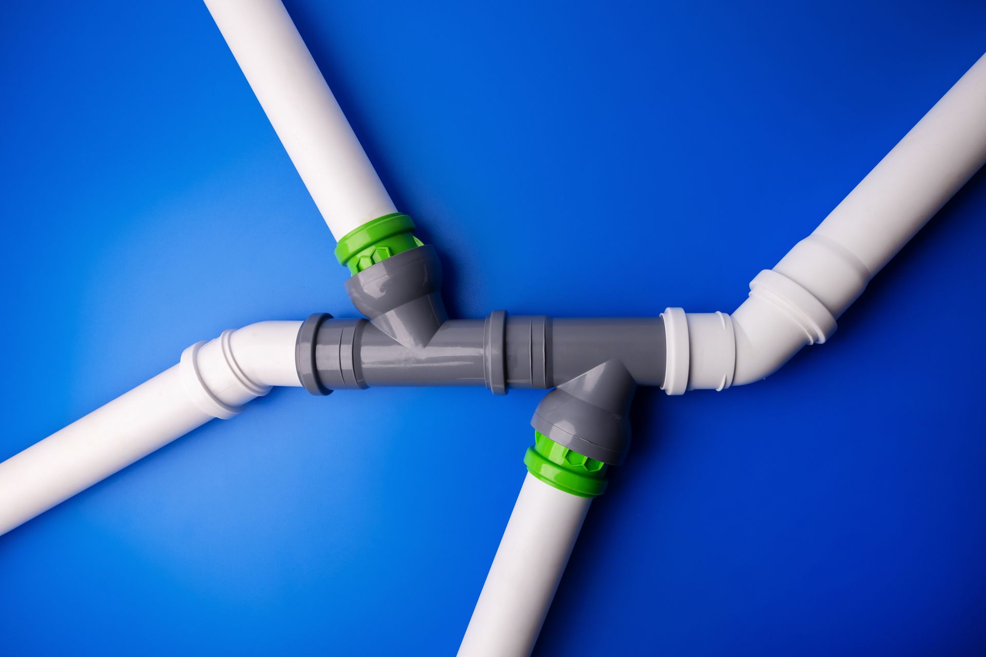 Raccords de canalisations en PVC avec coudes et jonctions sur fond bleu.