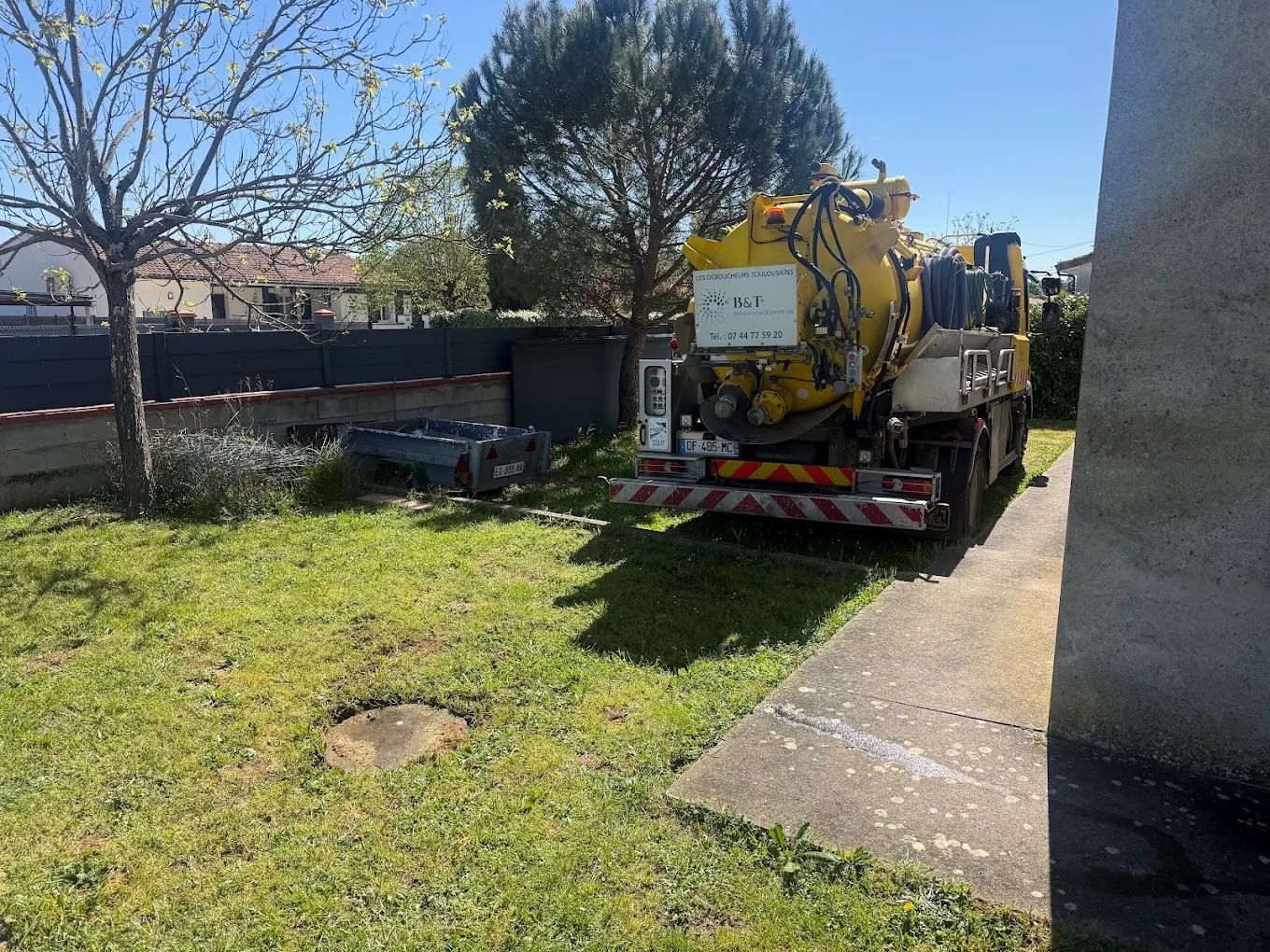 Camion hydrocureur pour débouchage et curage de canalisations stationné sur une pelouse.