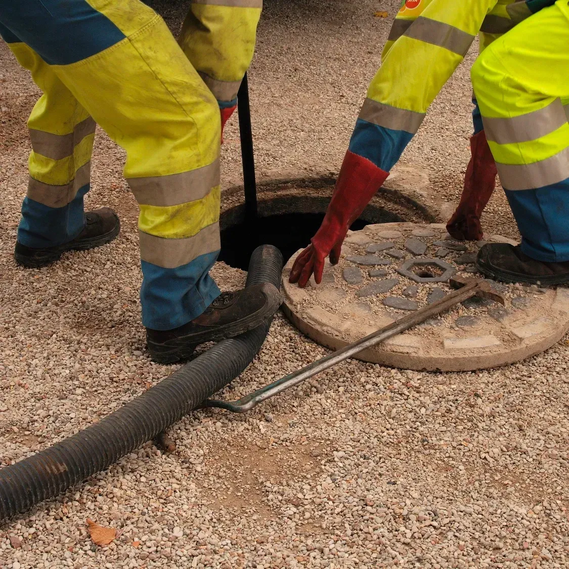 Deux employés travaillent sur une bouche d'égout