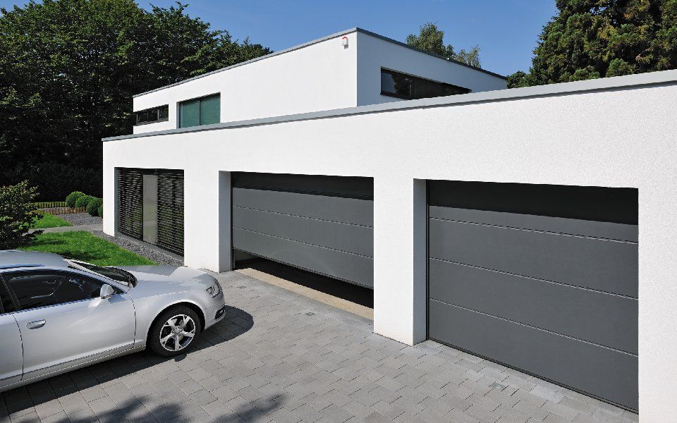 Zwei weiße Garagen mit grauen Garagentoren