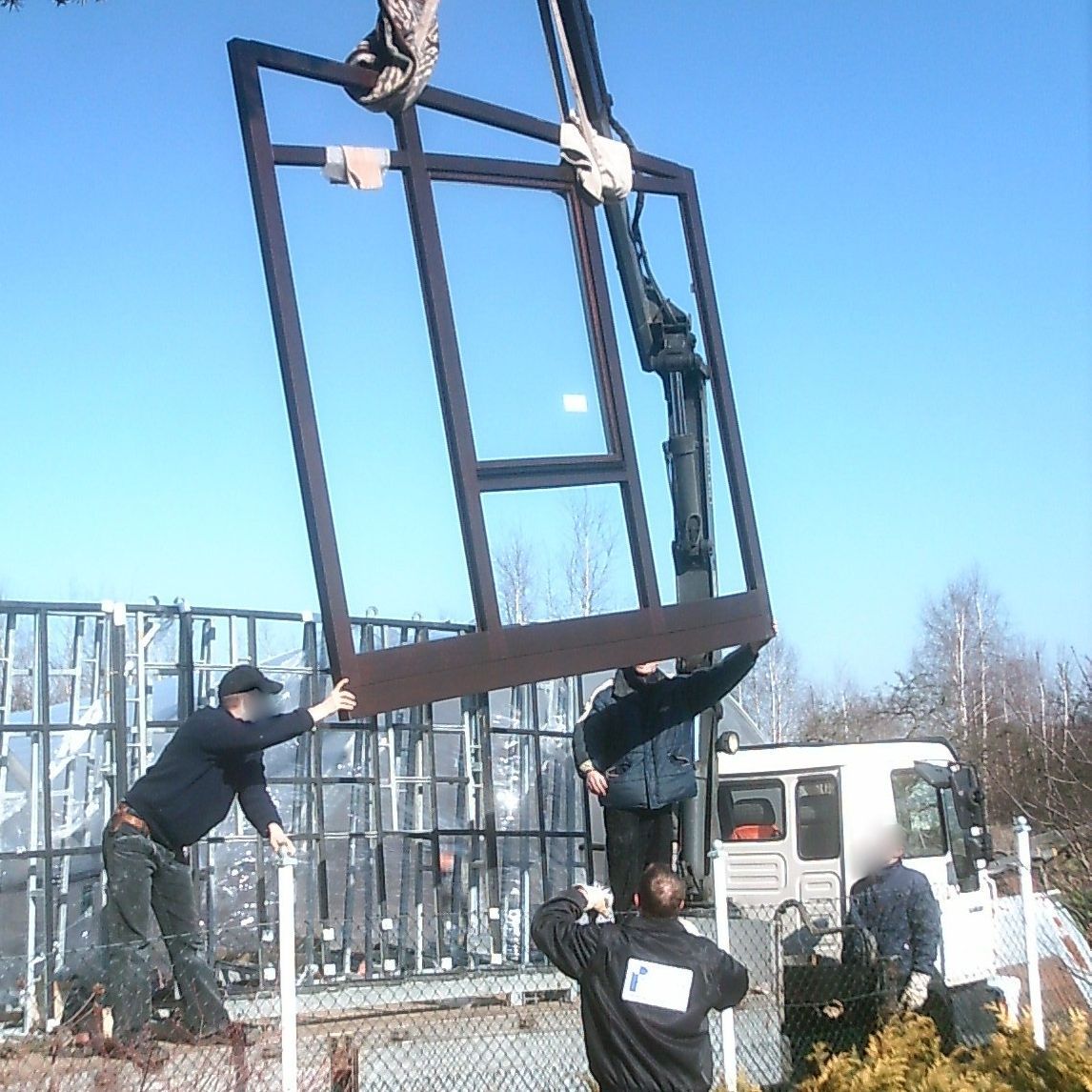 Glasfenster wird mit einer Hebebühne an den richtigen Ort gebracht.