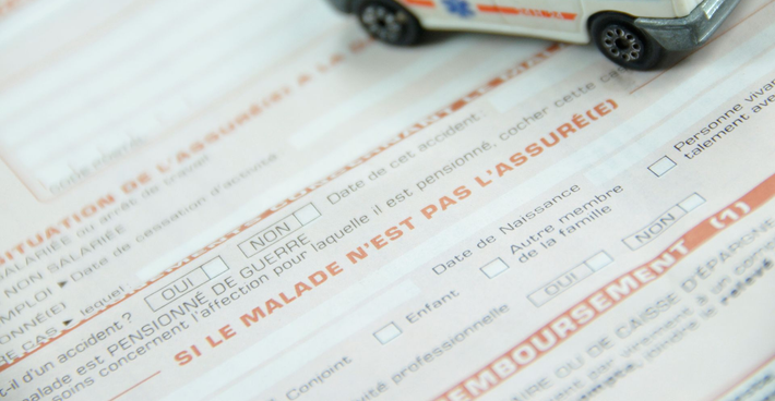 Gros plan sur un formulaire d'assurance maladie avec une petite voiture en haut.