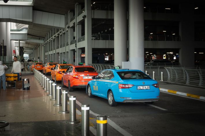 File de taxis orange et bleus attendant sous un porche couvert d'un aéroport