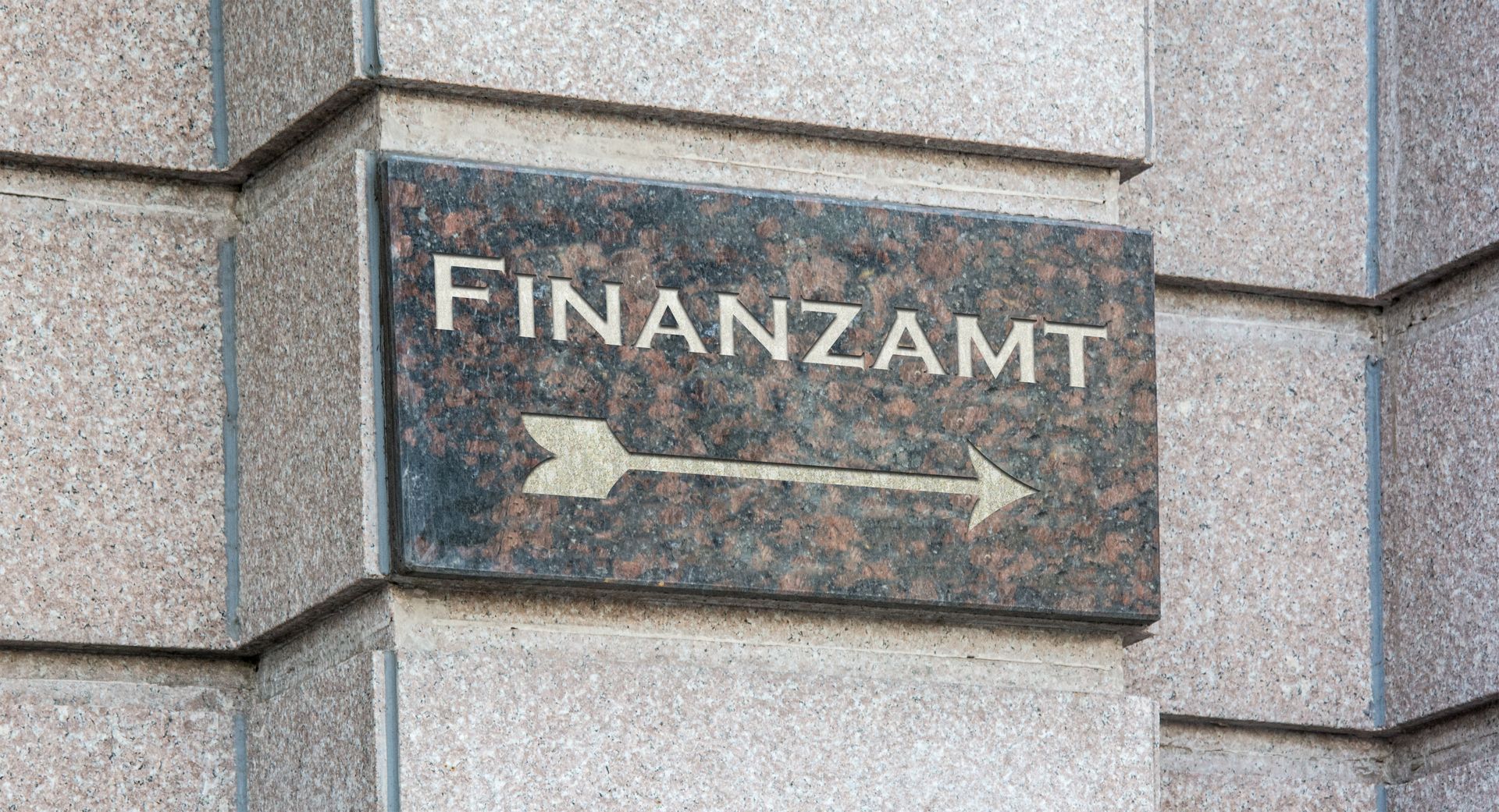ein Schild an der Seite eines Gebäudes zeigt den Weg zum Finanzamt .