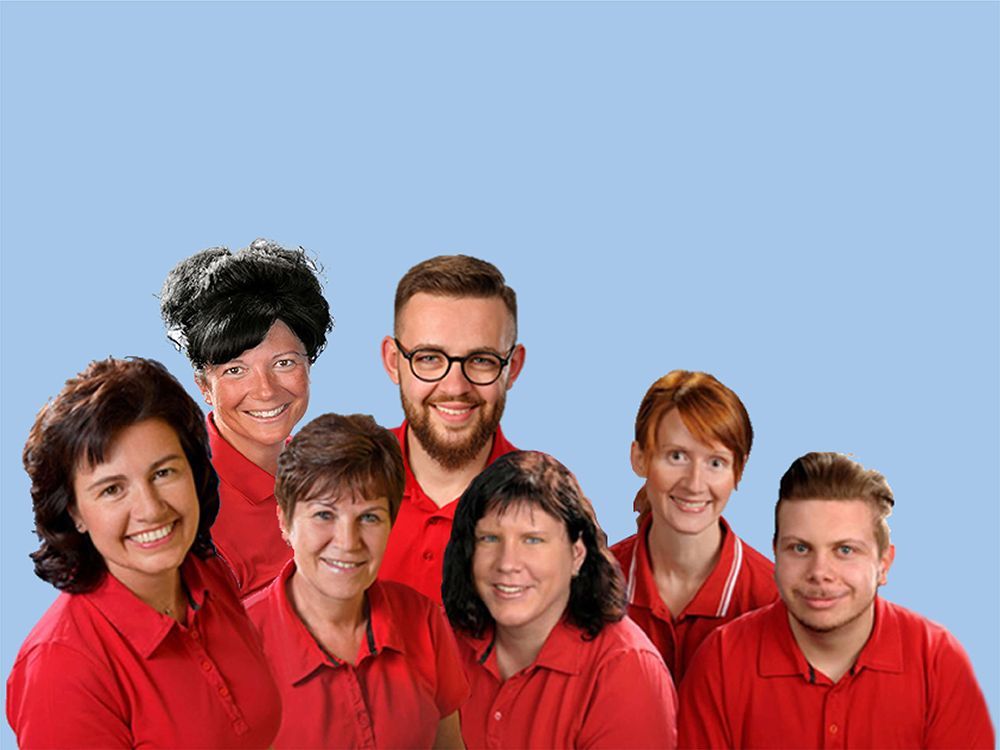 Gruppe von sieben Personen in roten Hemden, lächelnd, vor blauem Hintergrund.