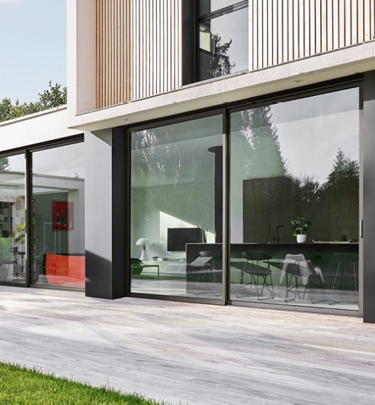 Maison moderne avec une baie vitrée, offrant un accès direct au jardin.