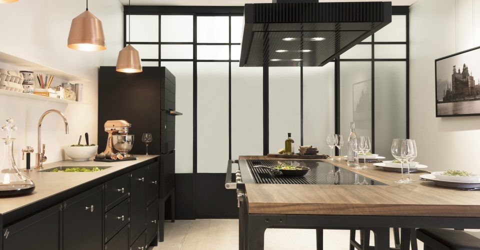 Cuisine design avec un îlot central, des meubles noirs et des éléments décoratifs comme des suspensions lumineuses.