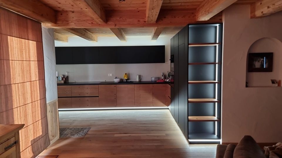 Une cuisine avec beaucoup d'armoires et d'étagères en bois dans un salon.