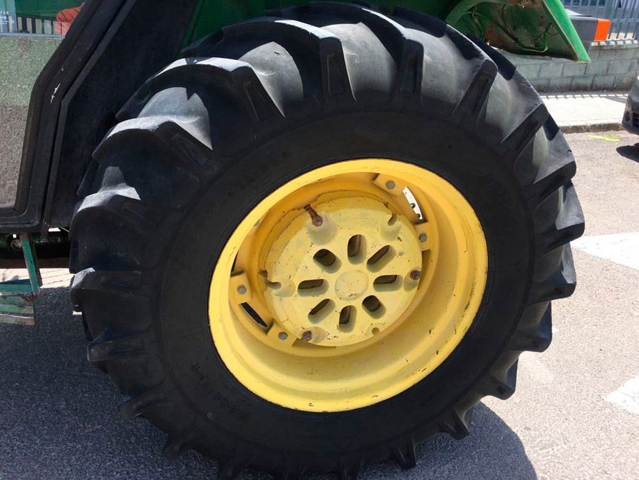Un primer plano de un neumático de tractor con una llanta amarilla.