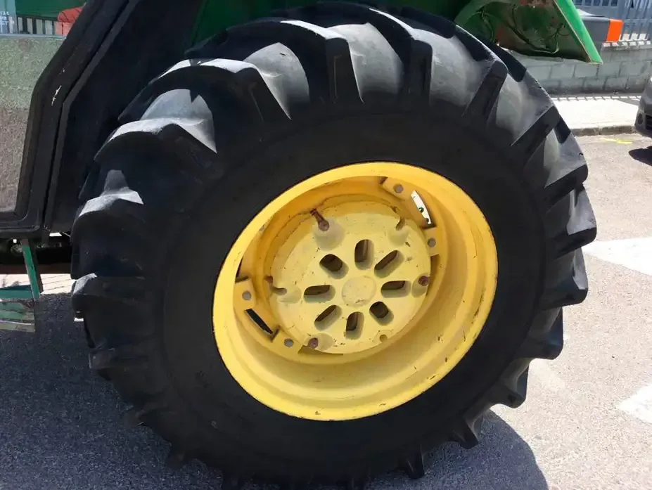 Un primer plano de un neumático de tractor con una llanta amarilla.