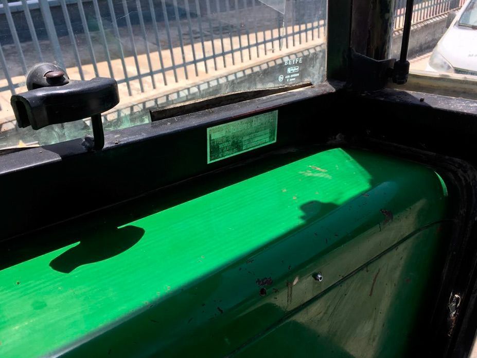 Un tractor verde está estacionado delante de una valla.