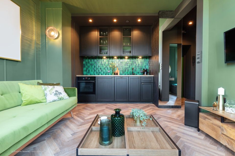 JK Fußbodenbau und Raumausstattung GmbH & Co. KG –  ein Wohnzimmer/Küchenbereich in grün-schwarzem Design, der Parkettboden bildet einen eleganten Kontrast