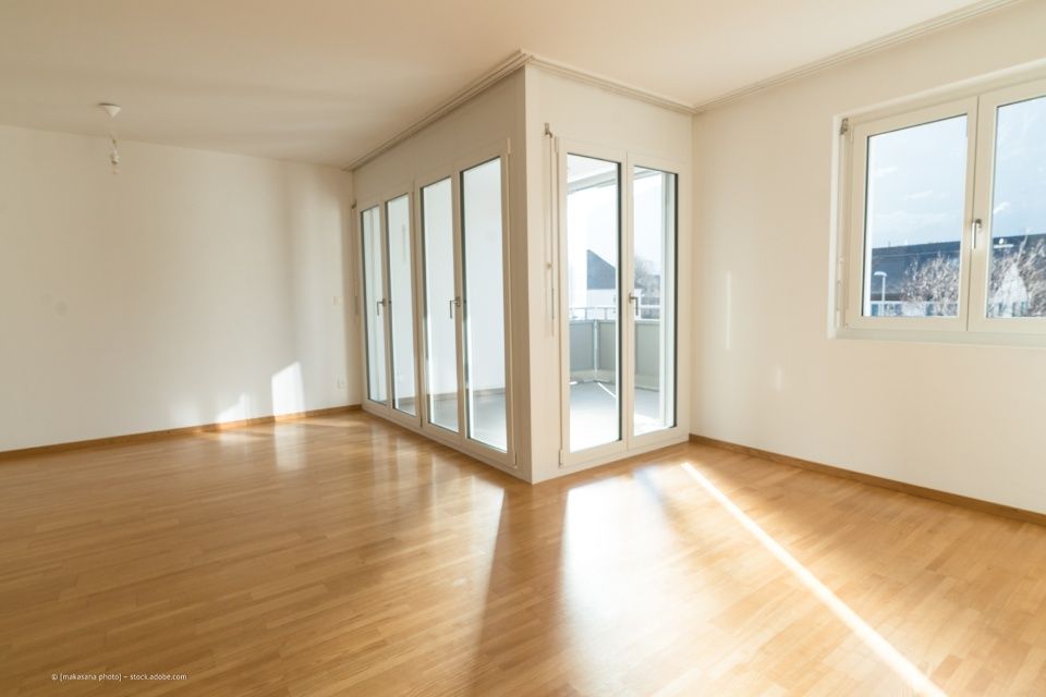 JK Fußbodenbau und Raumausstattung GmbH & Co. KG – Raumecke eines Wohnzimmers mit Blick auf den Balkon. Laminat ziert den Boden.