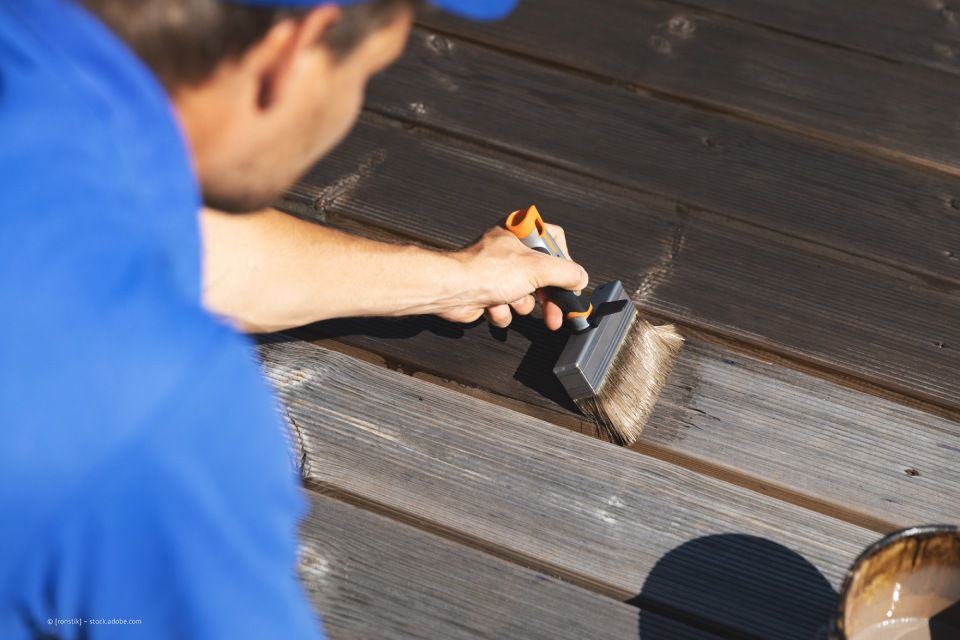 JK Fußbodenbau und Raumausstattung GmbH & Co. KG – ein Mann mit Pinsel versiegelt einen Holzboden