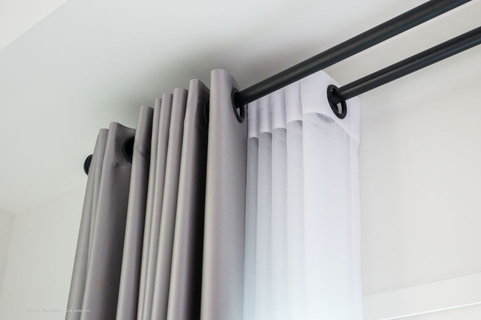 JK Fußbodenbau und Raumausstattung GmbH & Co. KG – ein Set grauer und weißer Plissees an einer Gardinenstange