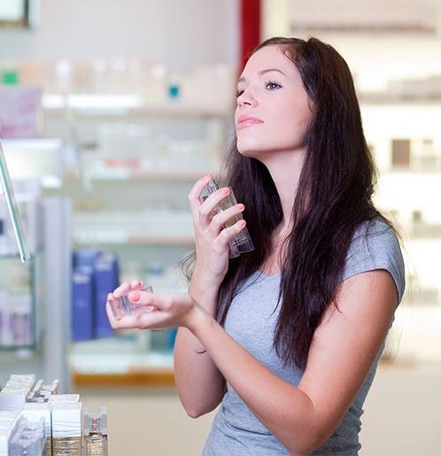 Una mujer se rocía perfume en la cara en una tienda.