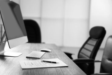 Schreibtisch mit Computerbildschirm und Papieren