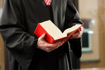 Person im Talar mit Gesetzbuch in der Hand