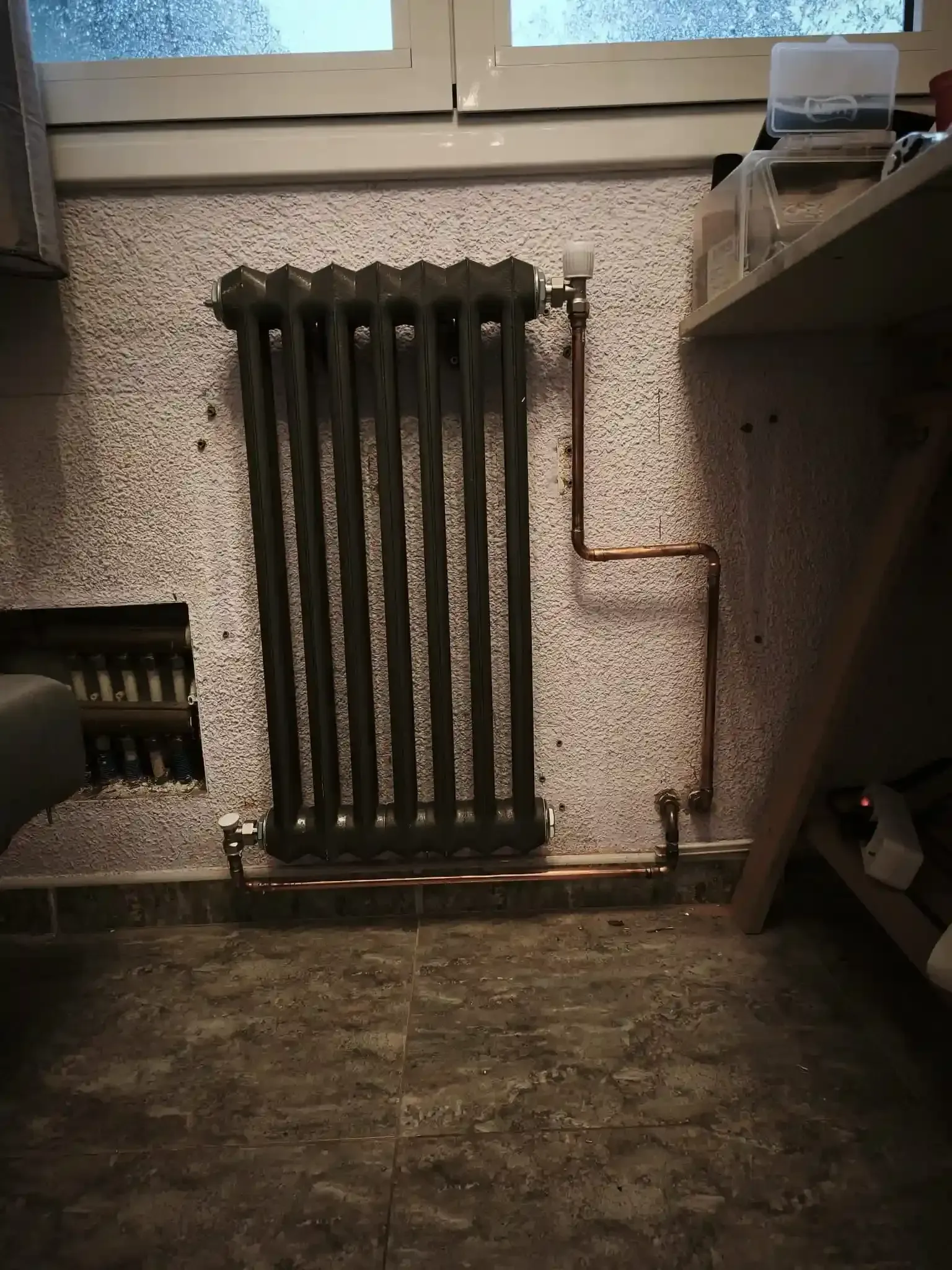 Un radiador oscuro y vertical montado sobre una pared texturizada y estampada