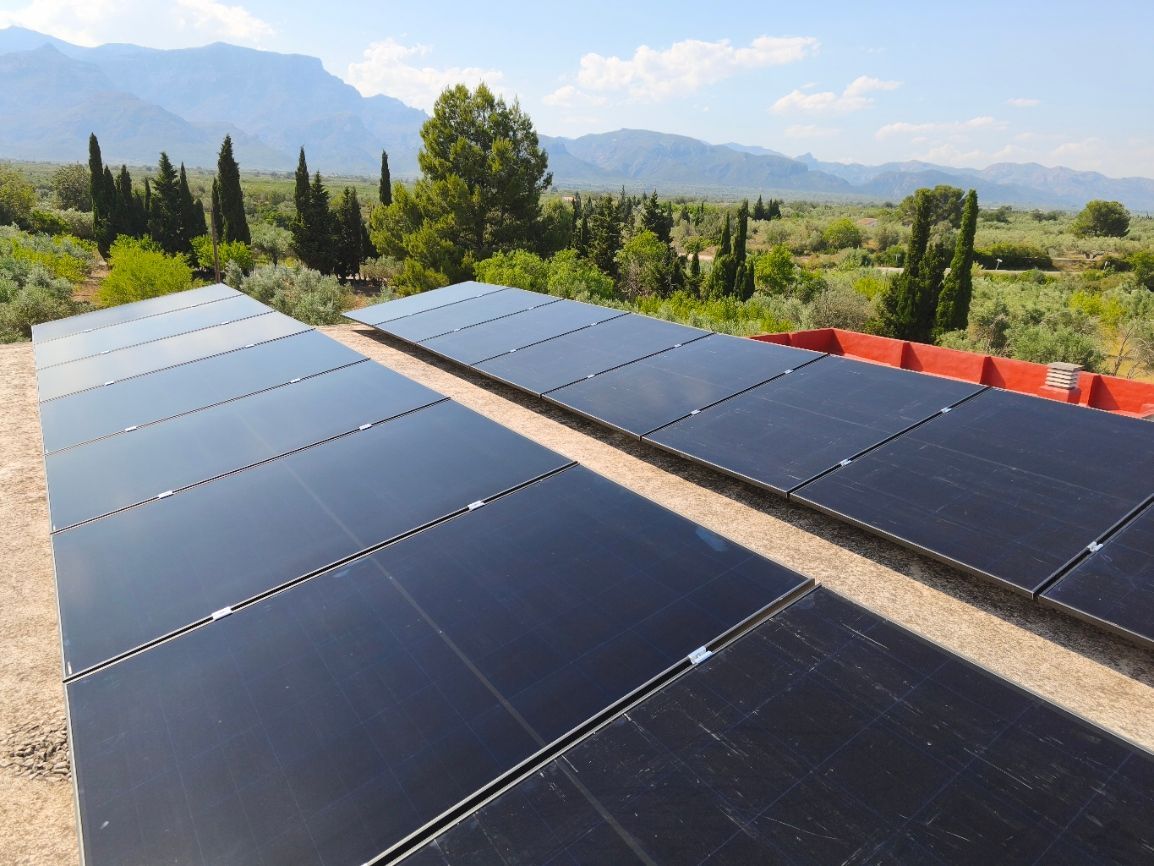 Paneles solares instalados en una estructura terrestre en un campo seco bajo un cielo azul despejado.
