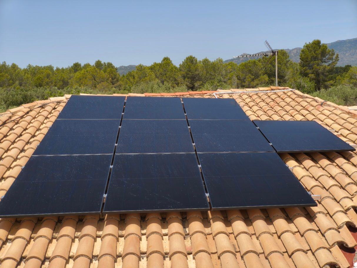 Paneles solares instalados en una estructura terrestre en un campo seco bajo un cielo azul despejado.