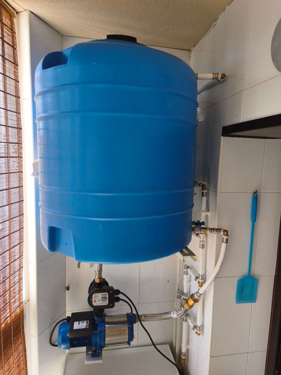 Tanque de almacenamiento de agua azul con bomba en un cuarto de servicio estrecho
