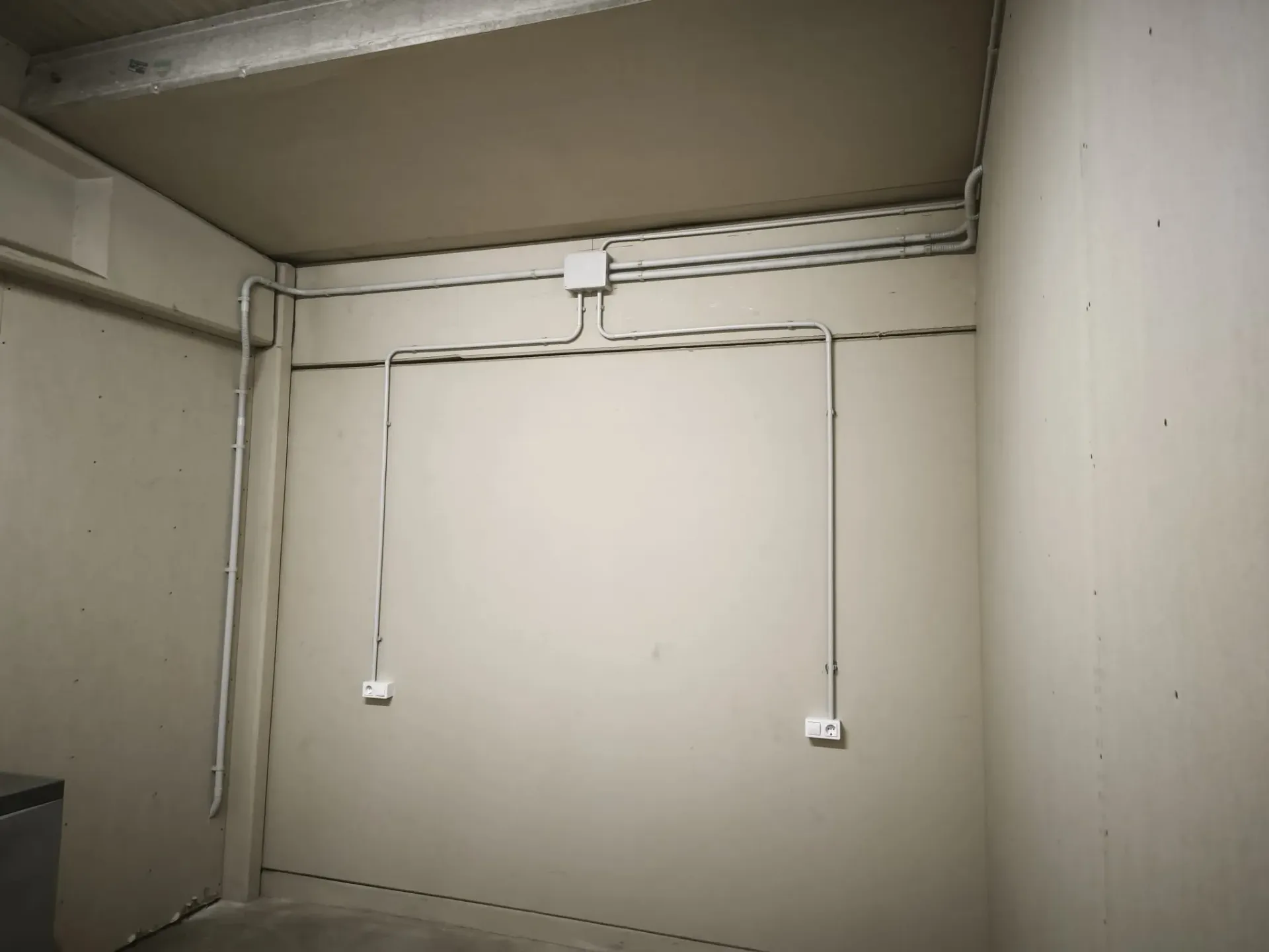 Cableado eléctrico y conductos instalados en una pared de color beige