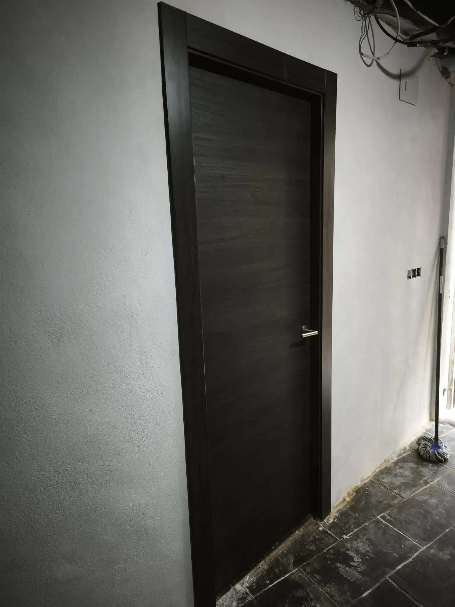 Una moderna puerta de madera oscura con tirador plateado