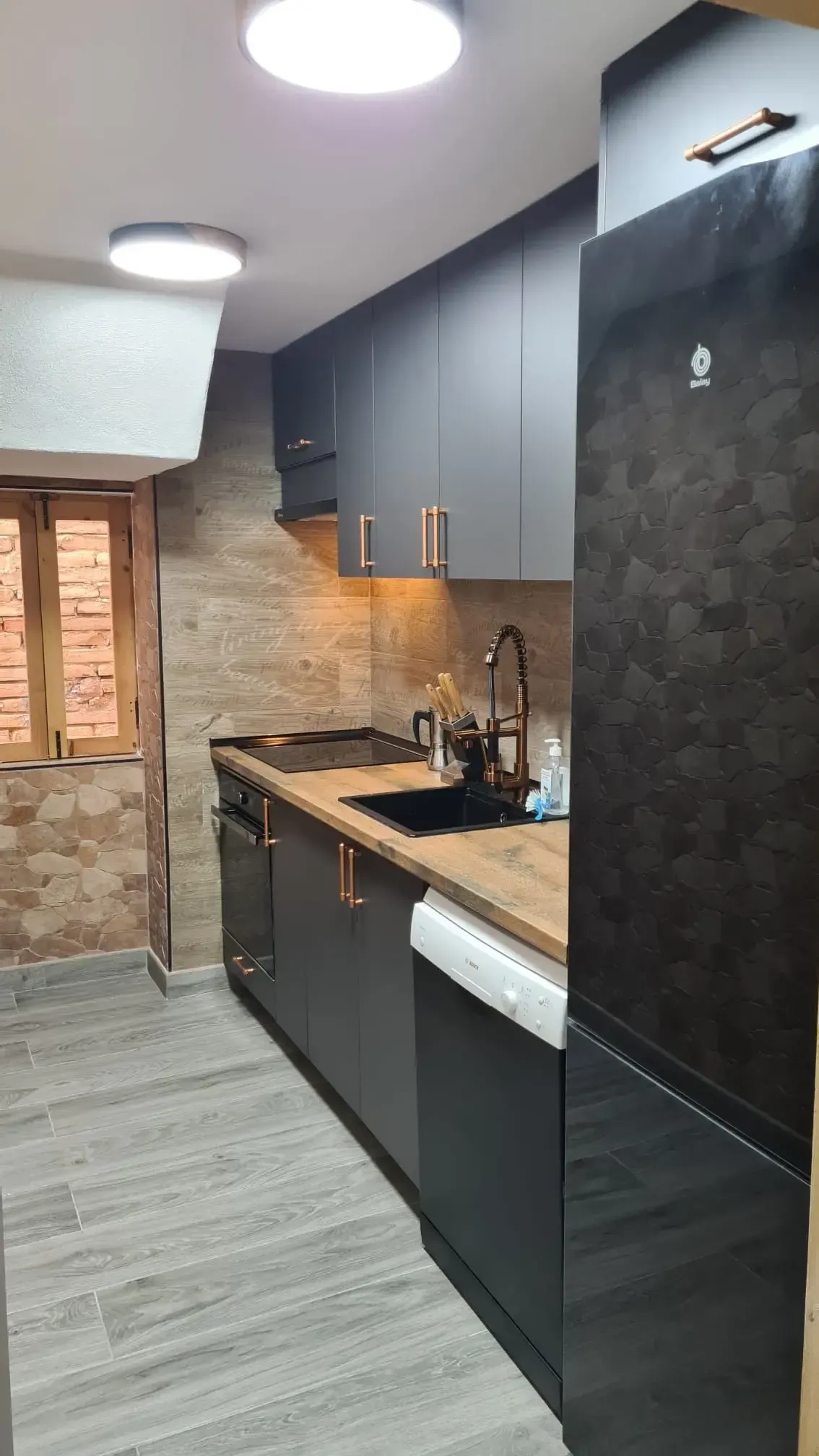 Una pequeña cocina con armarios de color gris oscuro