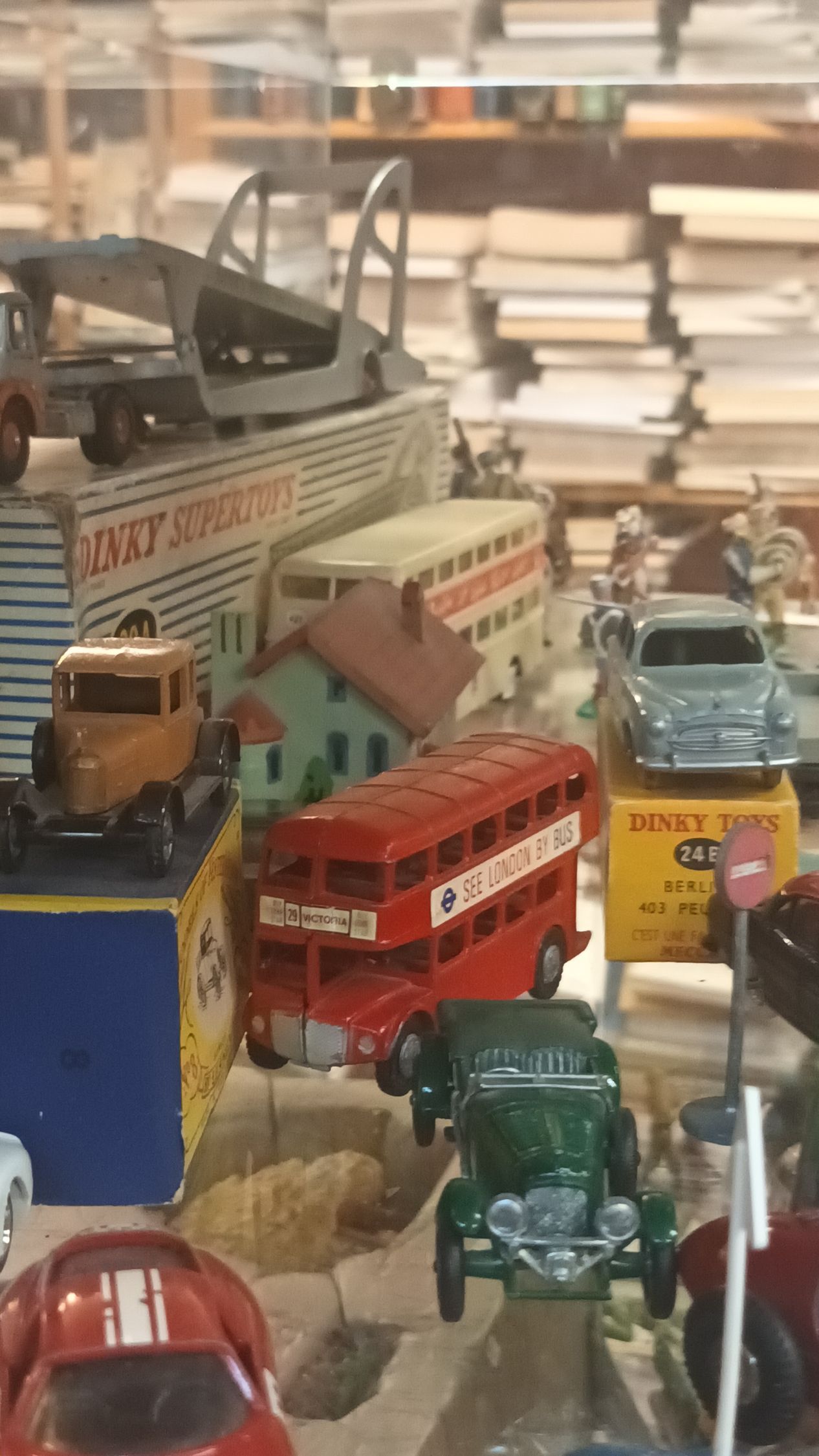 Une collection de véhicules miniatures anciens, comprenant des bus, des voitures et un porte-voitures, disposés sur une surface.