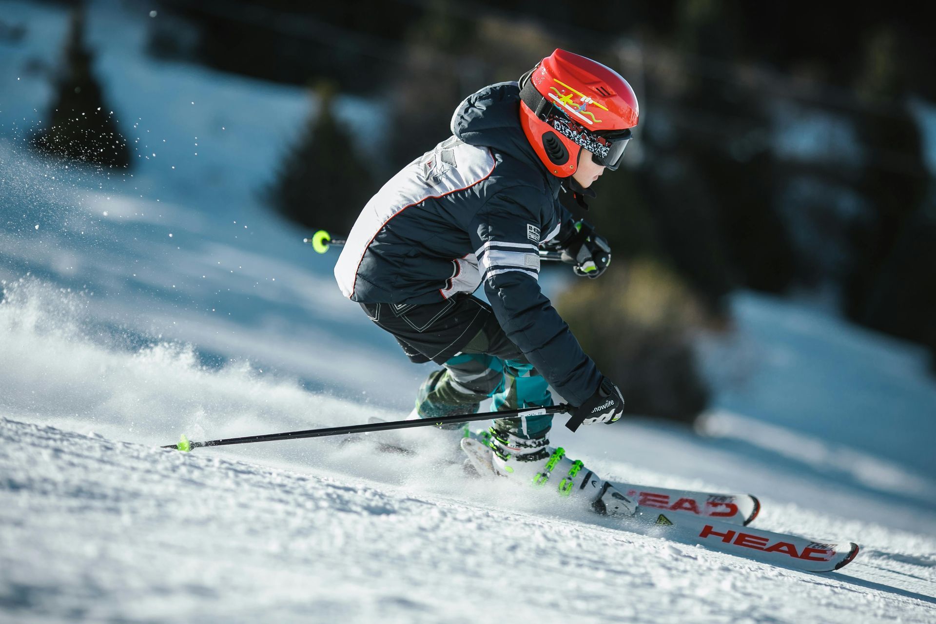 Skieur sur une pente enneigée, portant un casque orange, une veste noire et des skis.