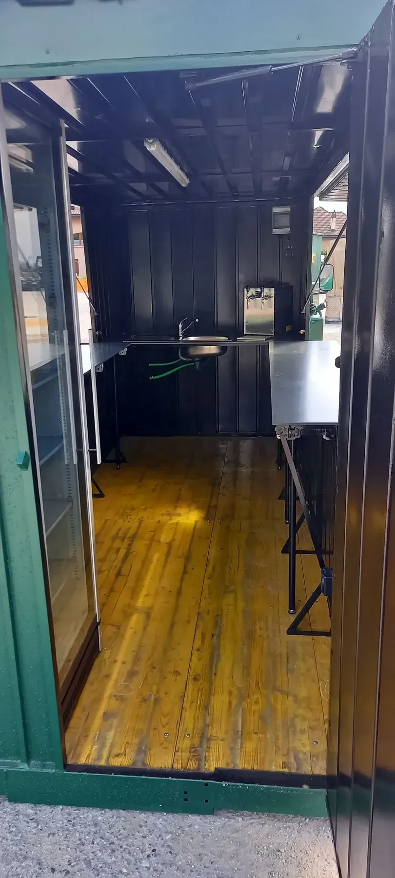 Une cuisine avec un plancher en bois et une porte verte.