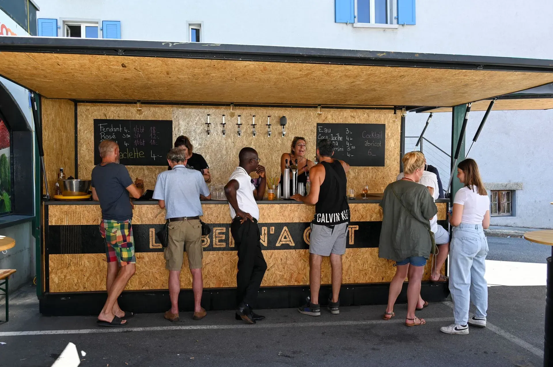 Un groupe de personnes se tient autour d'un bar en bois.