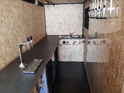 Une cuisine avec un évier, une cuisinière et des bouteilles accrochées au mur.