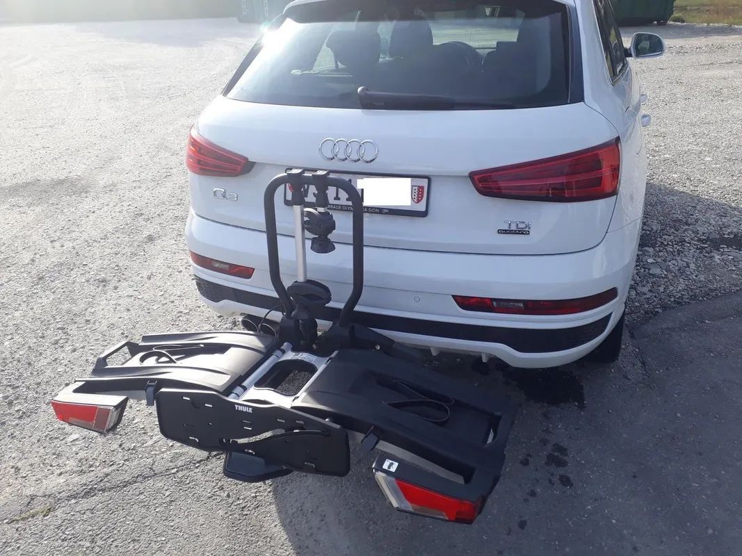 Une Audi blanche avec un porte-vélos attaché à l'arrière.