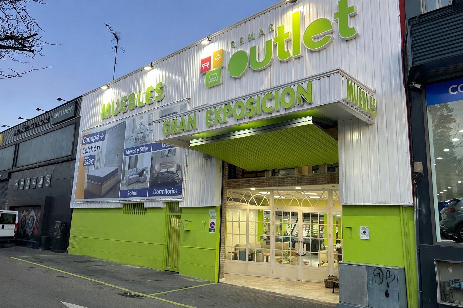 Almacén con sofás y plantas en macetas delante de cajas en estantes.