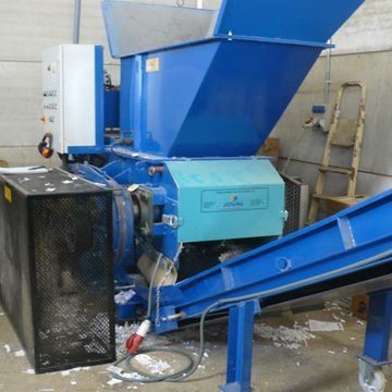 Máquina industrial azul con tolva y cinta transportadora en un taller