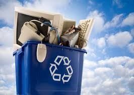 Contenedor azul de reciclaje desbordado de aparatos electrónicos desechados, bajo un cielo nublado