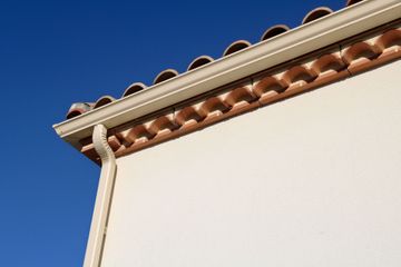 Mur en stuc blanc avec toit de tuiles en terre cuite.