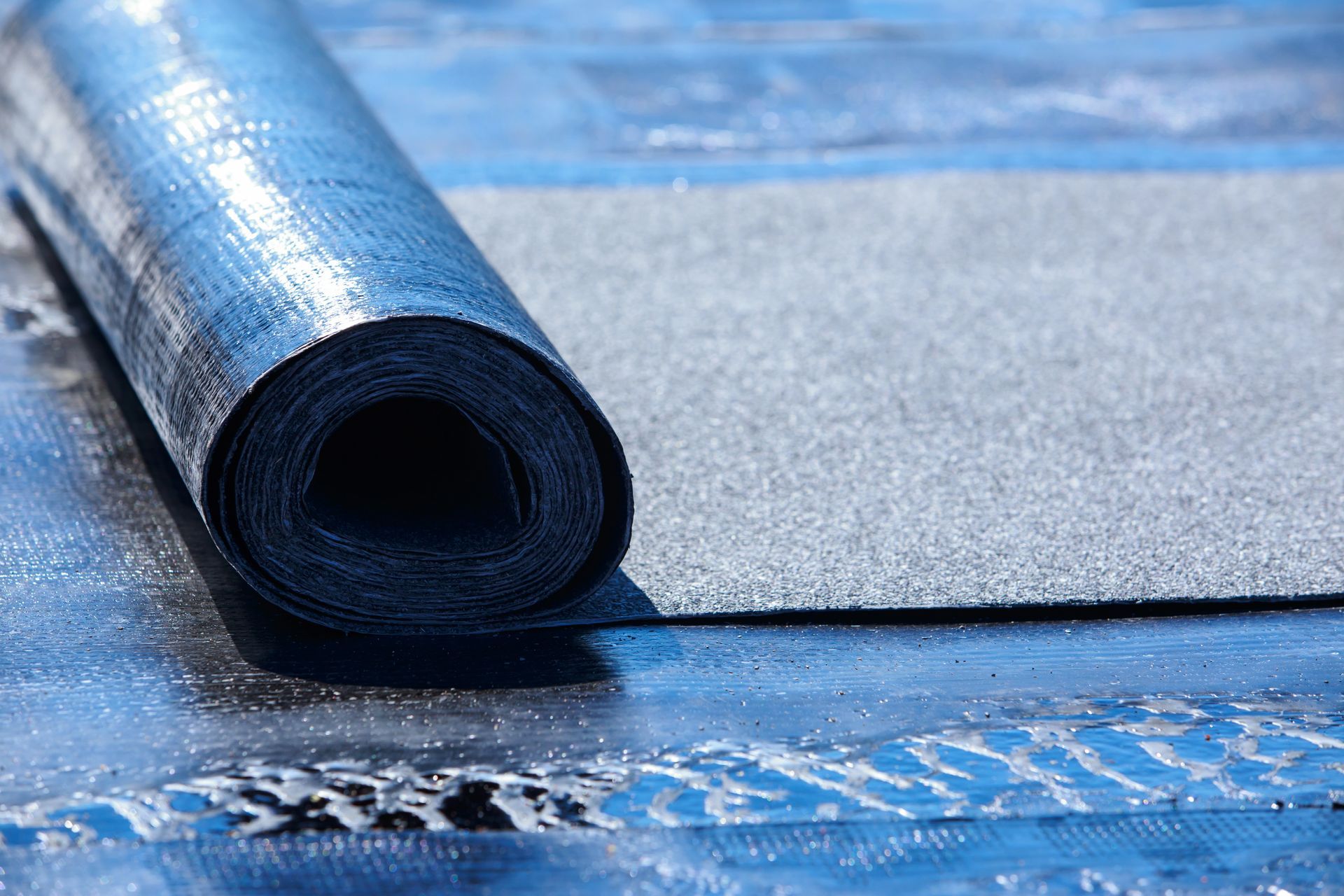 Membrane de toiture noire enroulée sur une surface de toit.