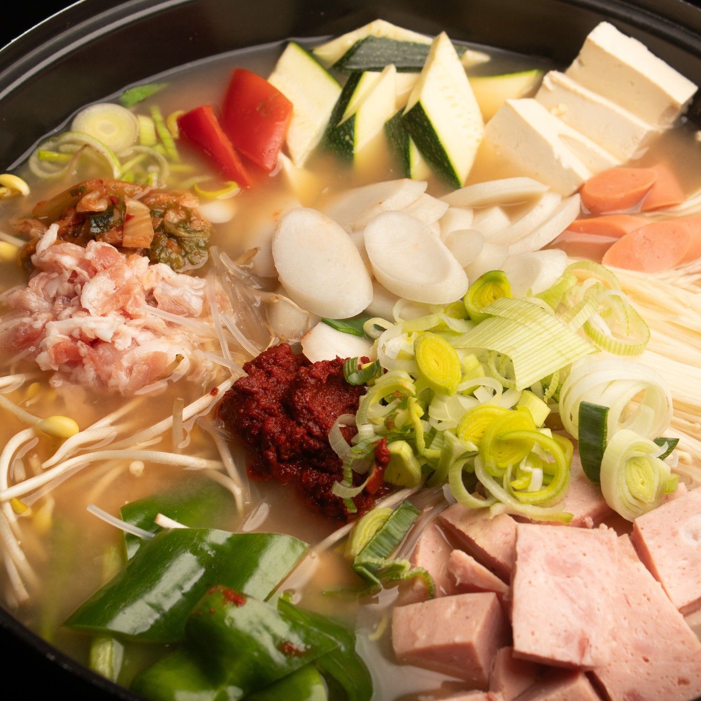 Hot pot coreano con verduras variadas, tofu, carne y guarniciones en un caldo a fuego lento
