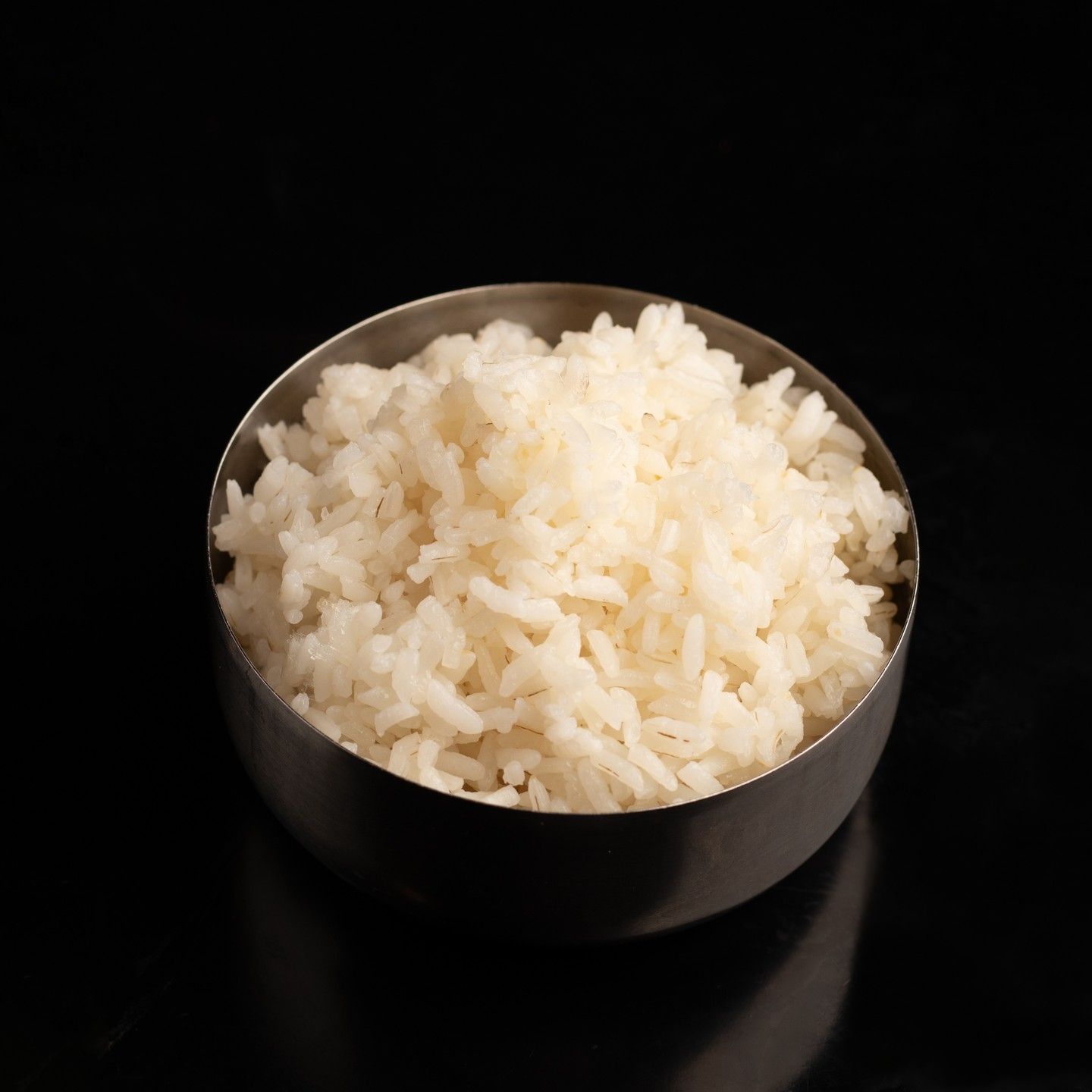 Un cuenco de arroz blanco esponjoso sobre un fondo oscuro