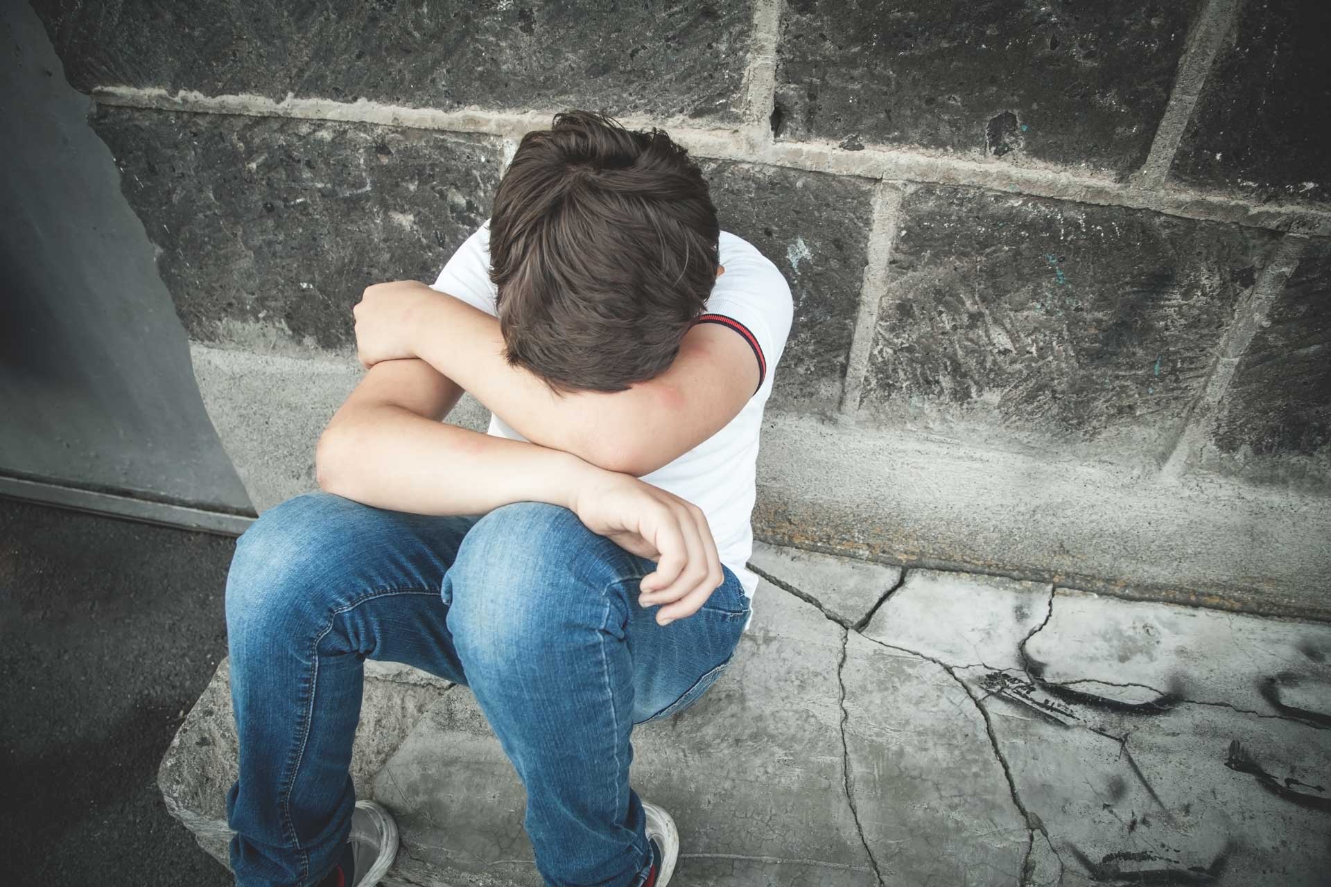 Jeune ado assis par terre la tête dans les bras