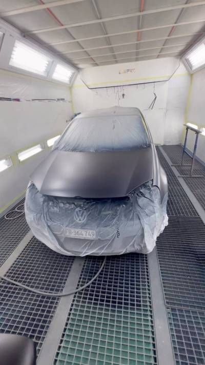 Une voiture est en train d'être peinte dans une cabine de peinture.